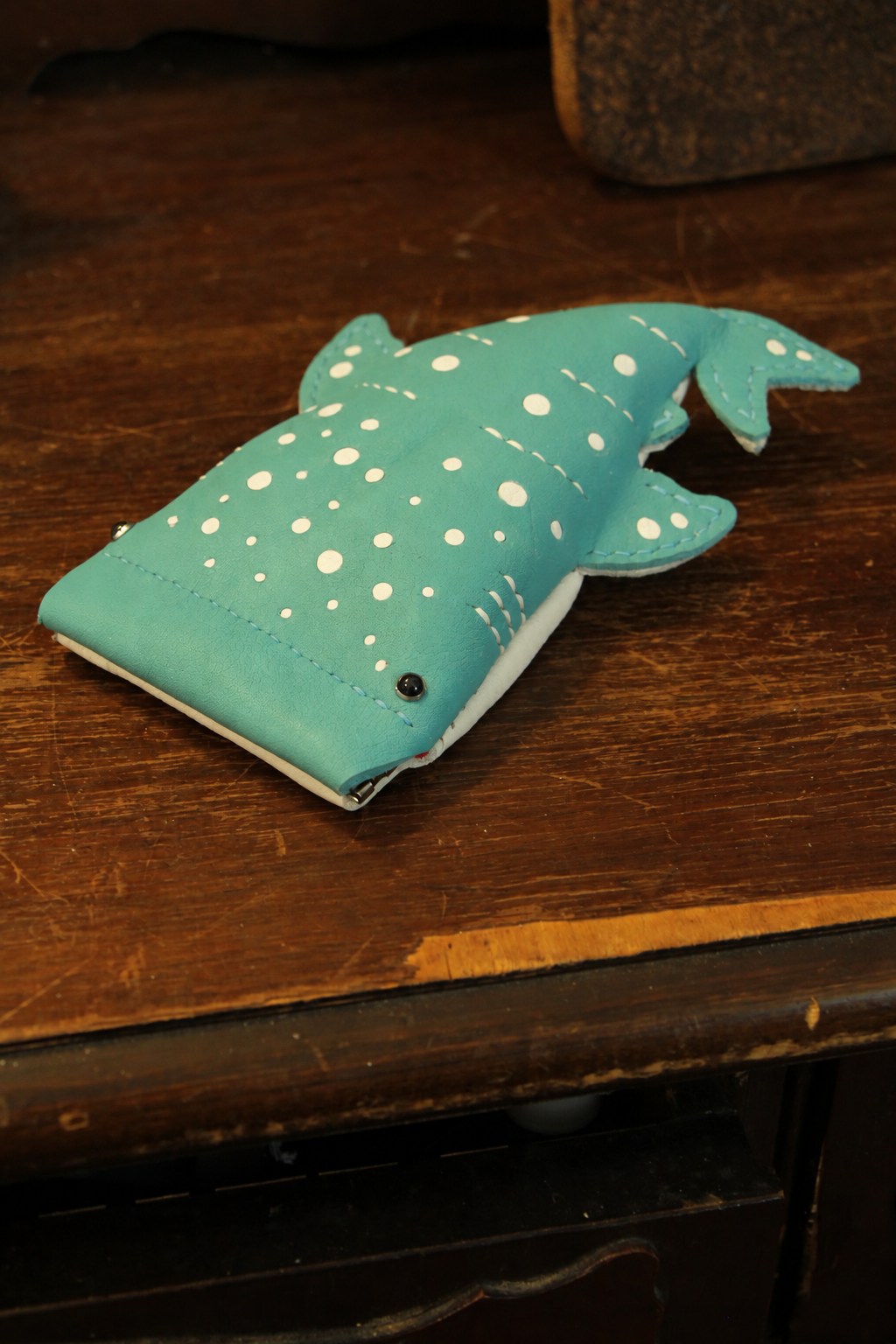 Turquoise Baby Whale Shark Wallet on a wooden table