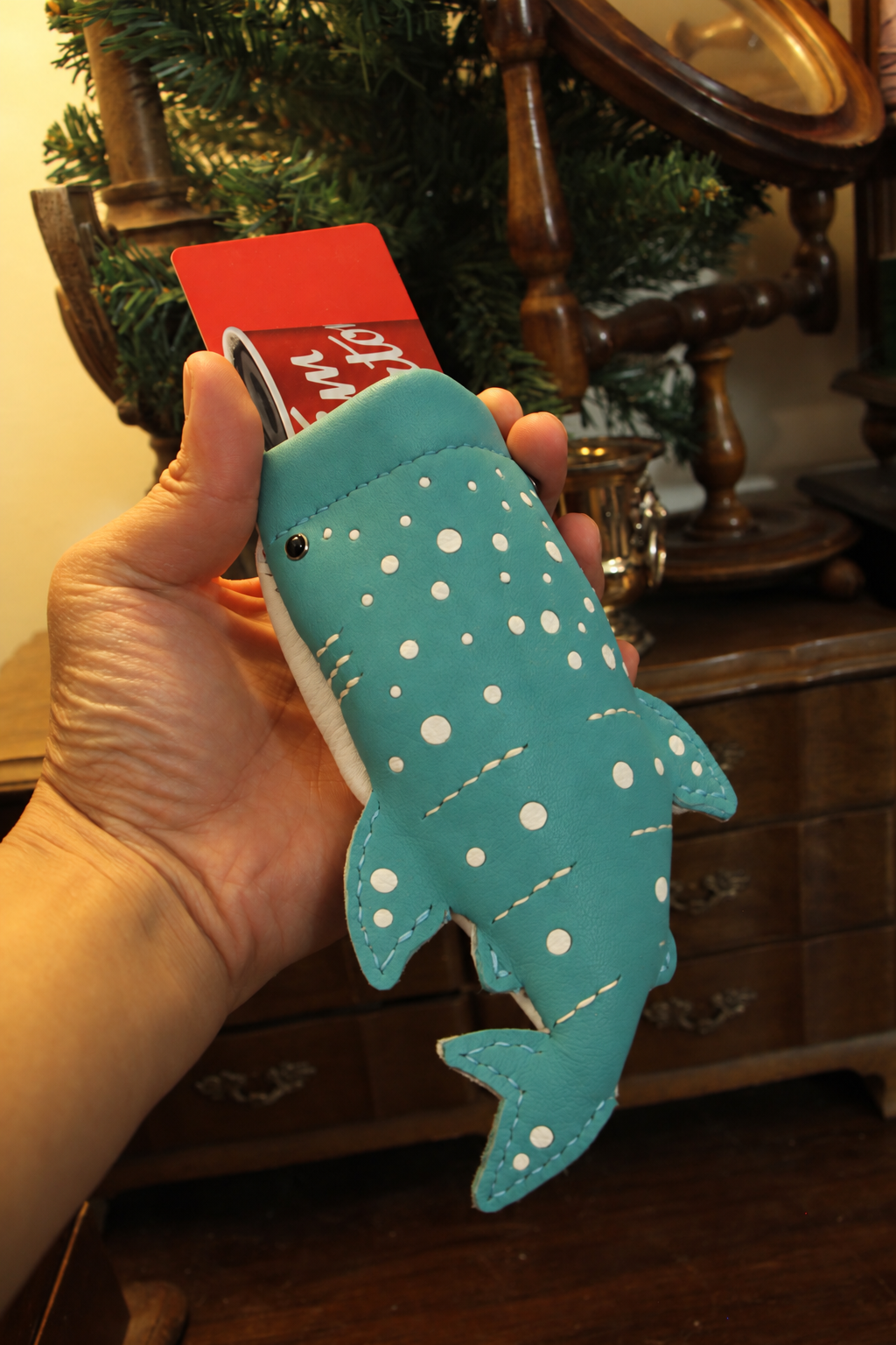 Turquoise Baby Whale Shark Wallet held in a hand with a card in its mouth